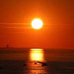Il sole si specchia sul mare accanto al Grattacielo di Rimini