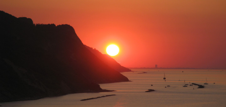 Il sole al tramonto sfiora il Monte San Bartolo