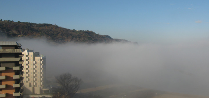 La nebbia copre la spiaggia e i primi palazzi in Baia